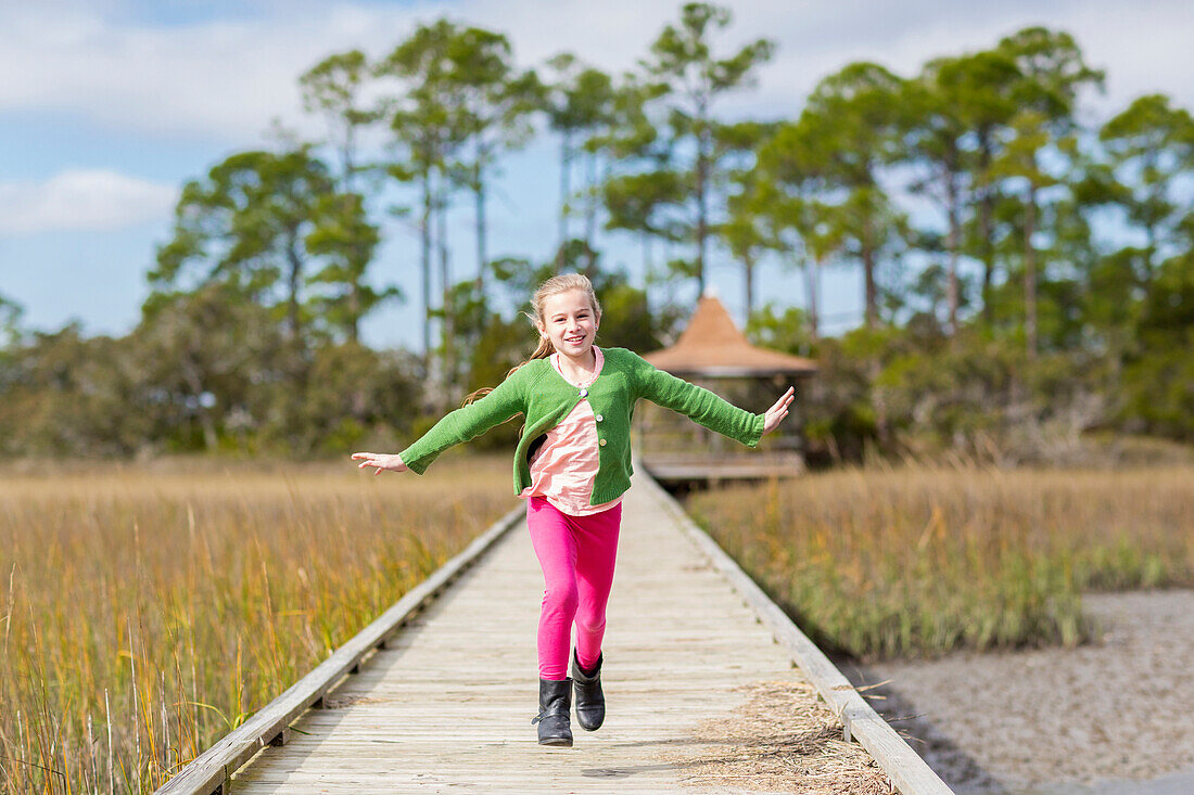 Caucasian girl running on wooden walkway, C1