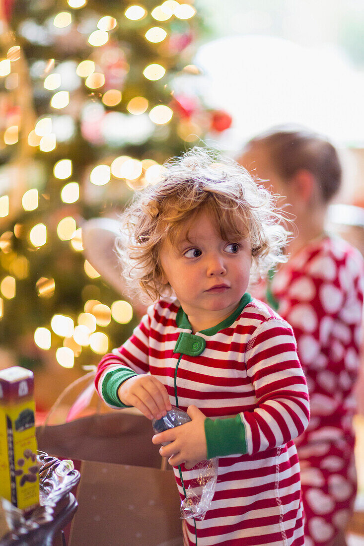 Caucasian baby boy opening present near Christmas tree, C1