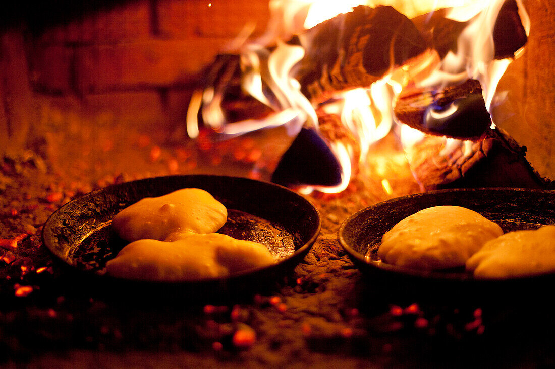 Close up of pastries cooking in skillets near wood fire, C1