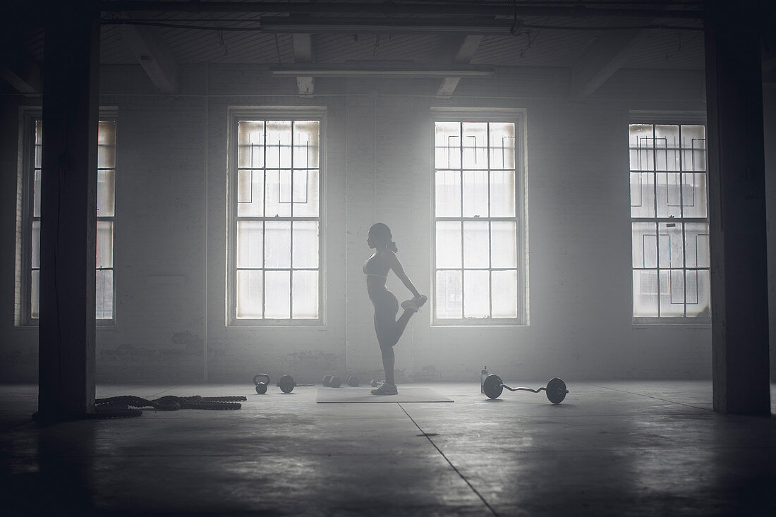 Schwarze Frau dehnt sich in einem dunklen Fitnessstudio, Saint Louis, MO, USA