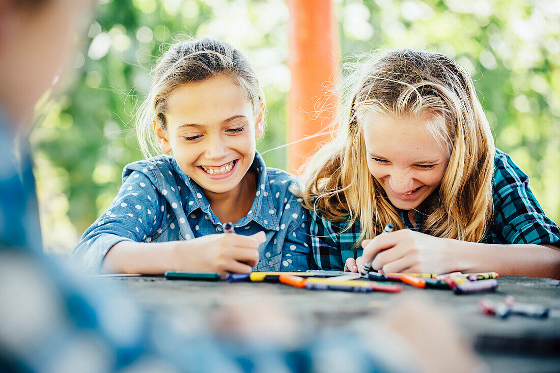 Smiling Caucasian girls coloring outdoors, Omaha, Nebraska, USA