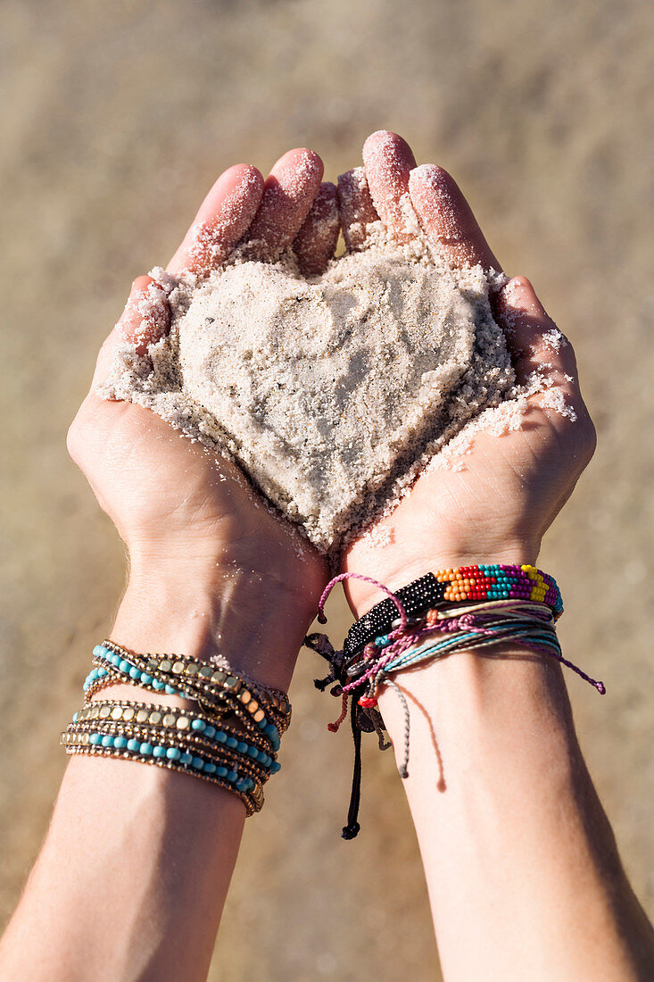 Close up of hands of Caucasian woman holding sand in heart shape, The Big Island, Hawaii, United States