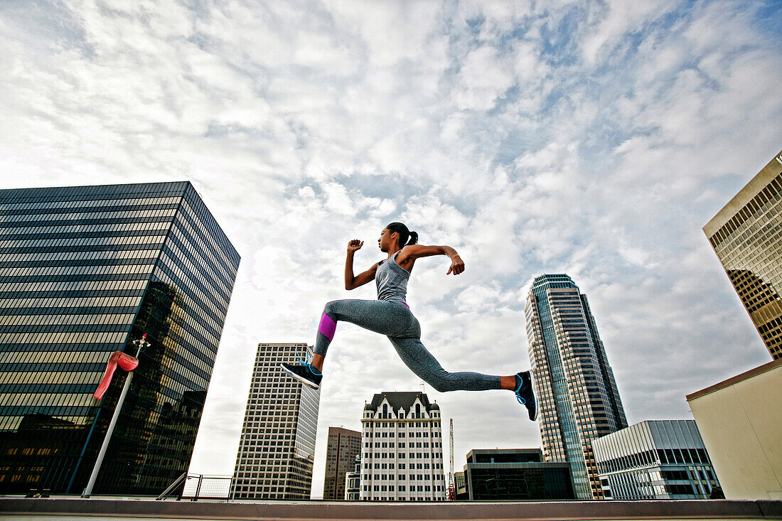 African American woman leaping on urban rooftop, Los Angeles, California, USA