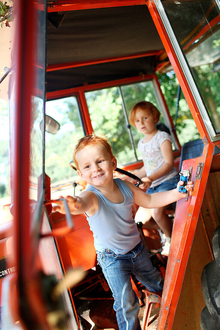 Young boy and young girl playing in a tractor in summer in the country