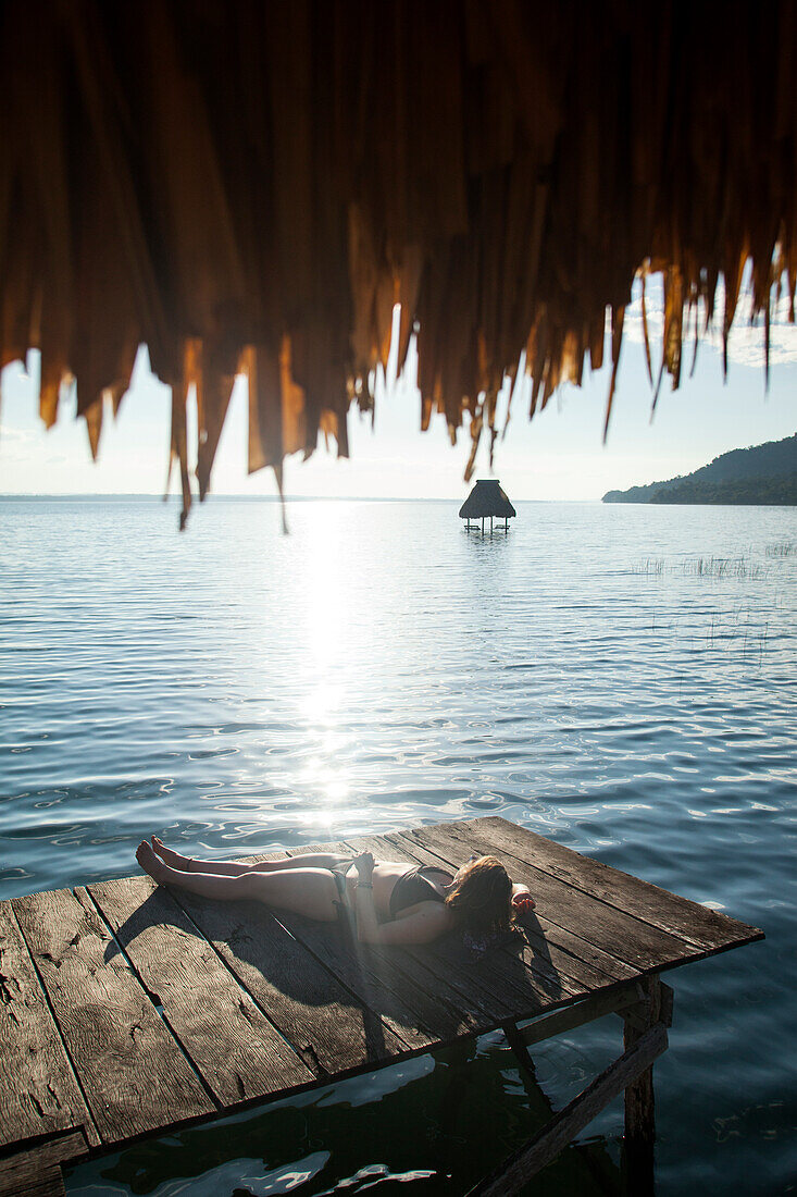 Woman relaxing on dock, El Remate, Lago Peten Itza, Guatemala, Central America