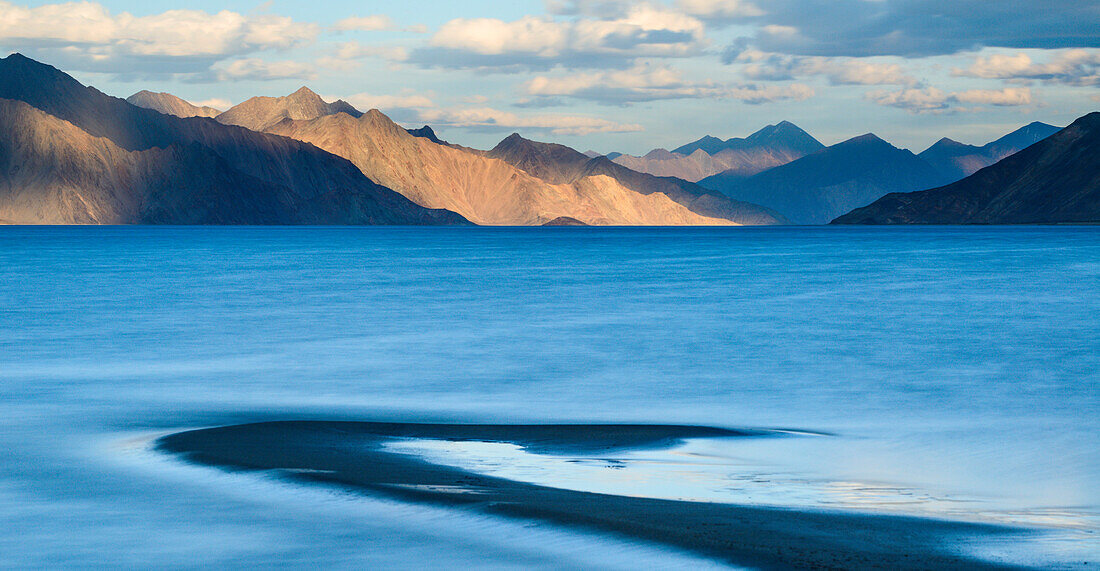 The turquoise, saline water of Tso Pangong, backed by mountains in the evening sun, Ladakh, India, Asia