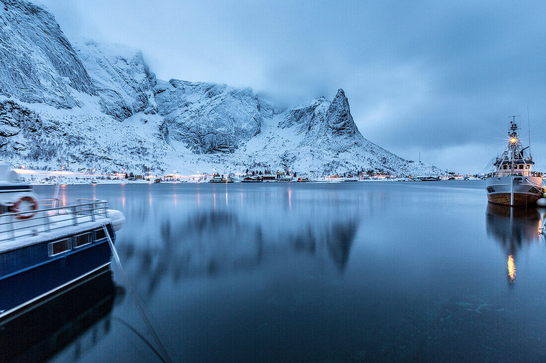 Ships moored in the small harbor of Reine under a gloomy sky in the south of the Lofoten Islands, Arctic, Norway, Scandinavia, Europe