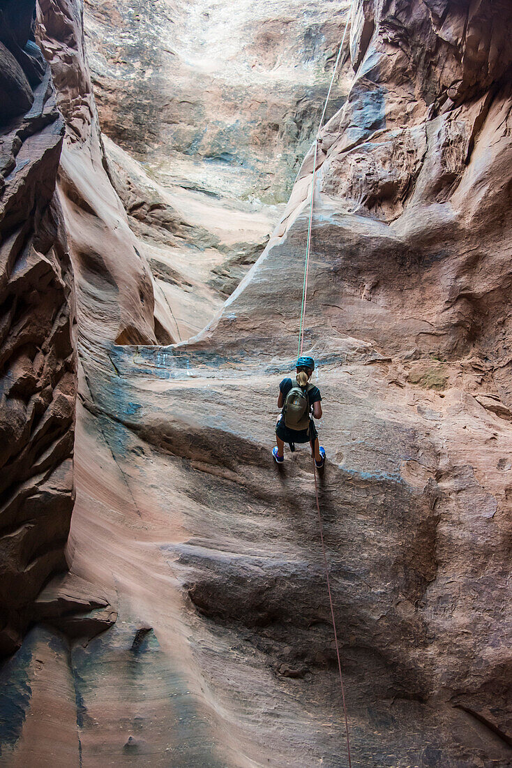 Woman rapelling down in slot canyon, canyoneering, Moab, Utah, United States of America, North America