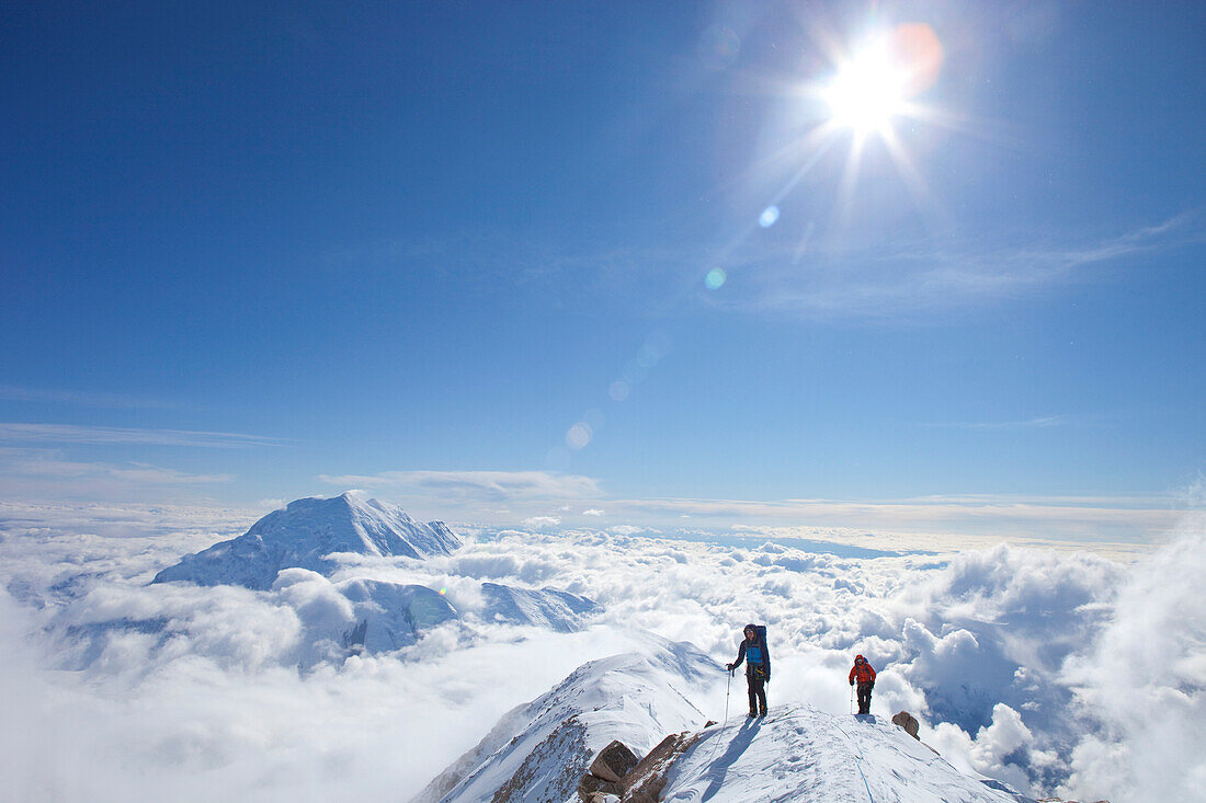 Two male climbers at the ridge between 14k and 17k camp on Mount McKinley, Alaska. They are above the clouds in blue sky and the sun is shining. Nevertheless it is very cold.    Mount McKinley, native name Denali, is the highest mountain peak in North Ame