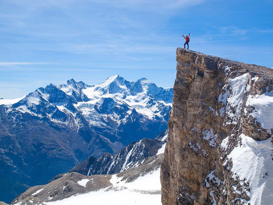 A male mountaineer is standing on the summit of the Barrhorn, a mountain peak of 3610 meter in the Swiss Alps. It is one of the highest summits in Europe to be accessible to experienced hikers. The region of Wallis is home to over 40 mountain peaks higher