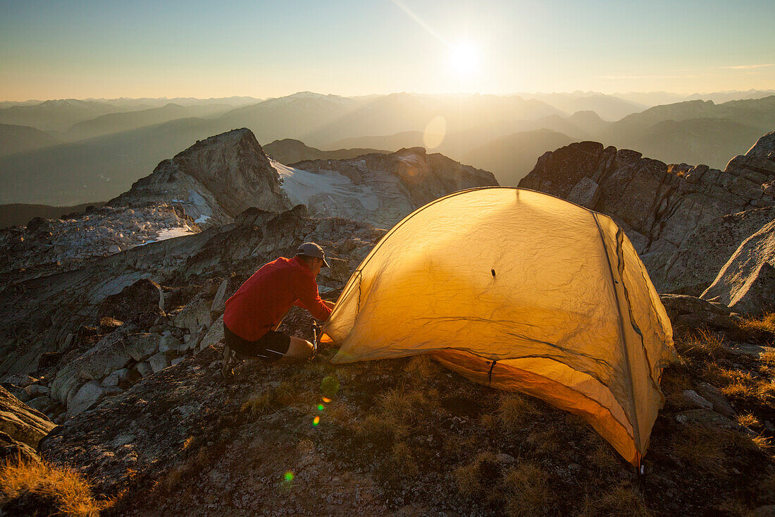 A hiker sets up a tent on the summit of Saxifrage Peak, Pemberton, BC, Canada.