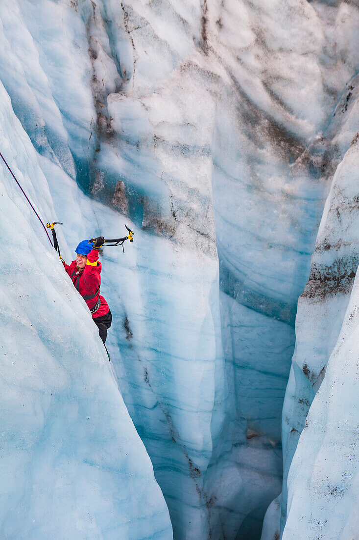 A man swings his ice tools as he climbs out of a moulin on a day trip with St. Elias Alpine Guides to the Root Glacier in Wrangell-St. Elias National Park, Alaska.