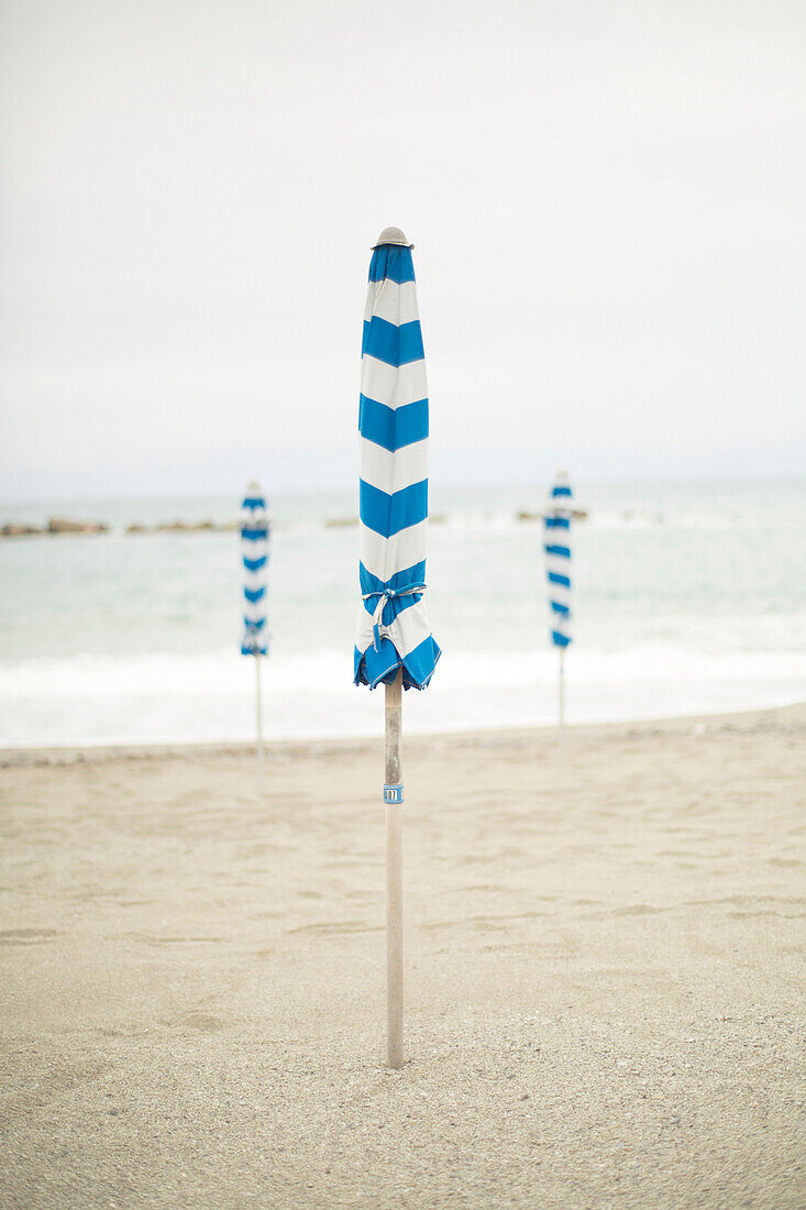 Umbrellas remain closed on an empty Italian beach.