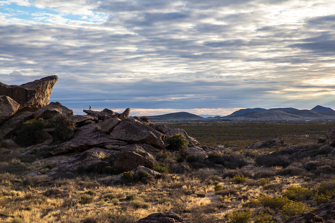 Hiker looks out on sunset of Hueco Tanks State Park, Texas