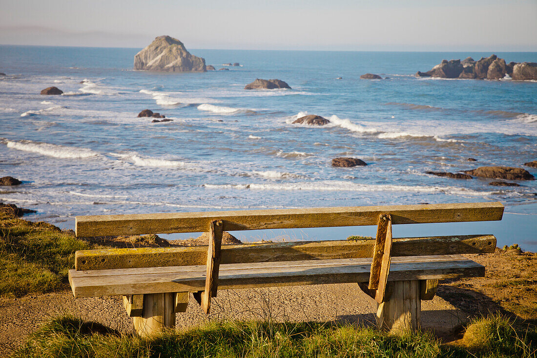 An old weathered wooden bench looks out at Bandon Bay, Oregon.