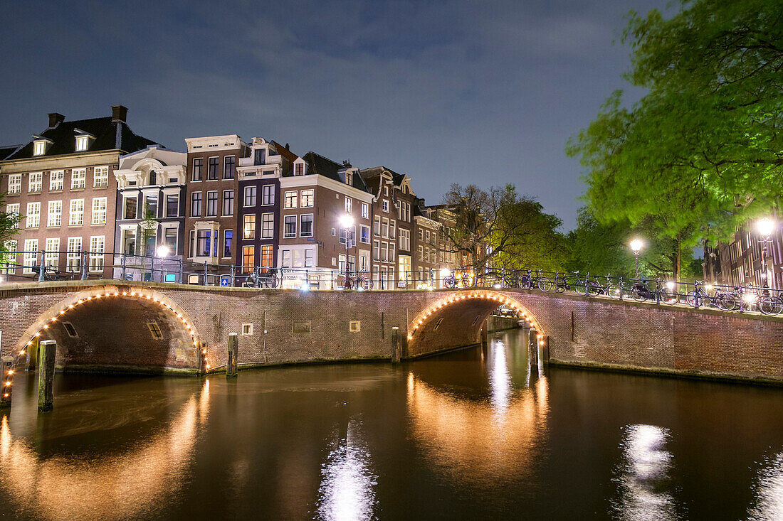Buildings and arched bridges at the intersection of Herengracht and Reguliersgracht at night, Amsterdam, North Holland, Netherlands