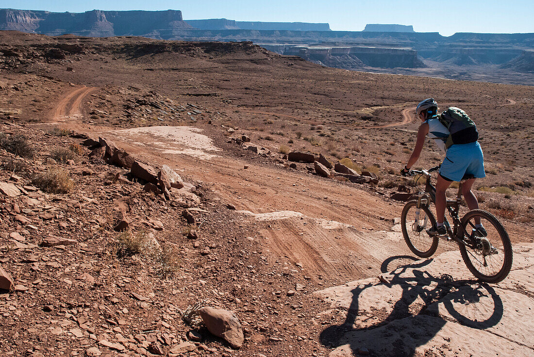 A woman in her early thirties mountain bikes the White Rim Trail near Moab, Utah.