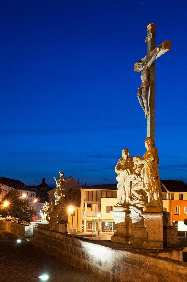 Statue of Crucified Jesus Christ on Kamenny Most, the oldest Gothic stone bridge in Czech Republic, at dusk, Pisek, Budejovicko, Czech Republic, Europe
