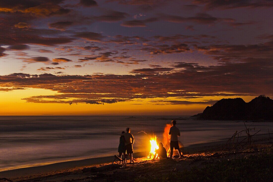 People with driftwood fire at sunset on Playa Guiones beach, Nosara, Nicoya Peninsula, Guanacaste Province, Costa Rica