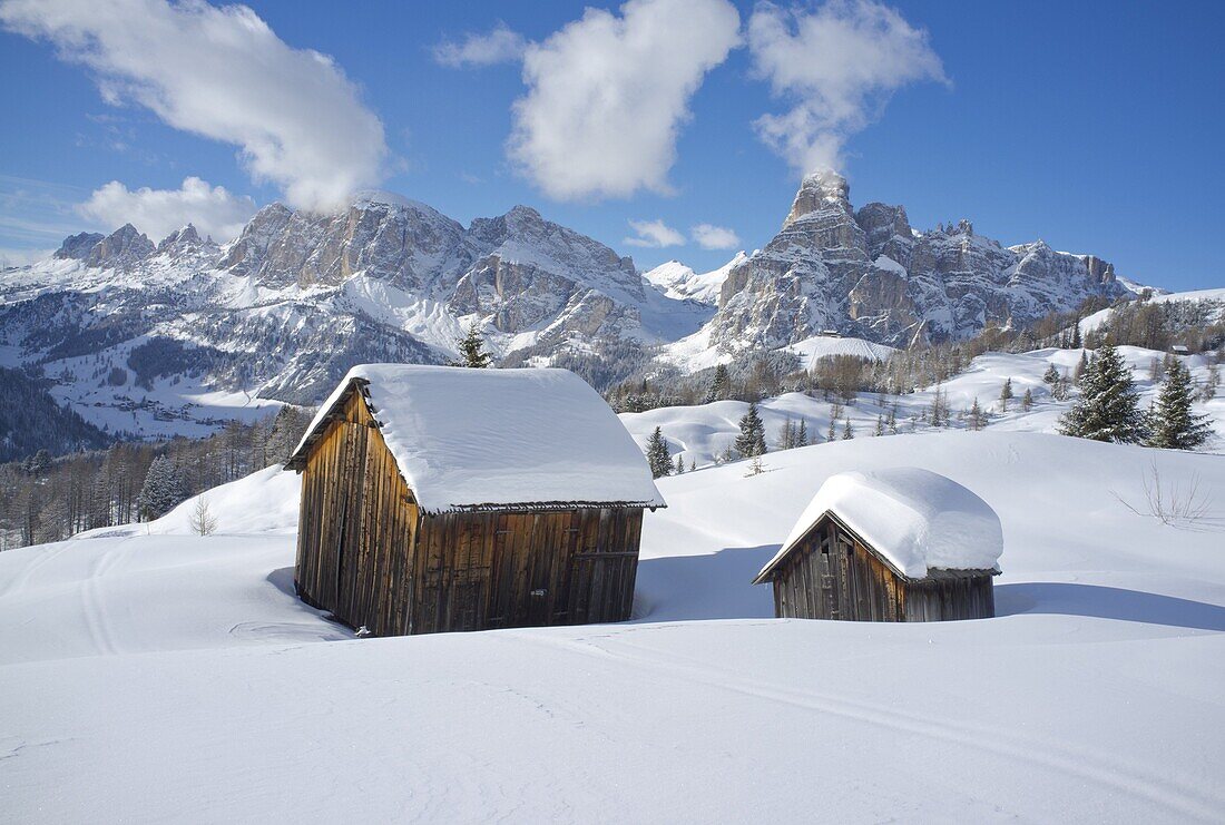 Mounts Lavarella, Conturines and Sasongher behind snow covered wooden barns at the Alta Badia ski resort near Corvara, Dolomites, South Tyrol, Italy, Europe