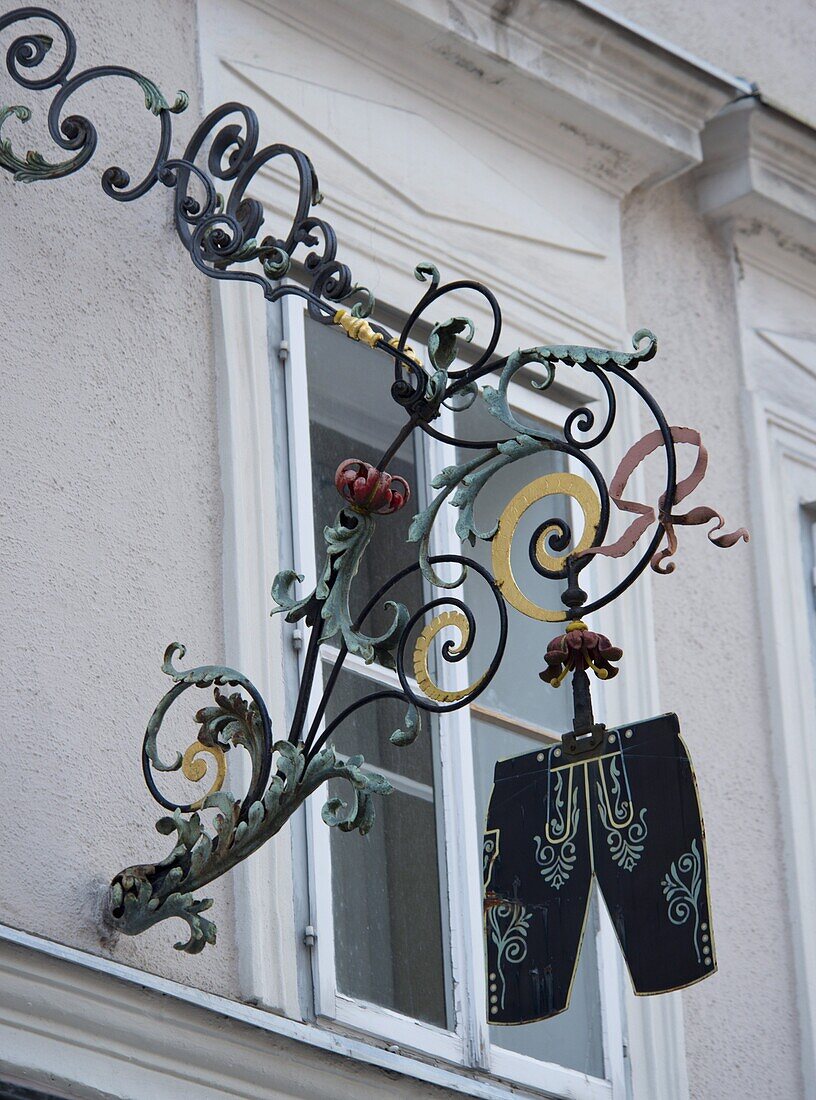 A traditional hanging sign in front of a shop selling lederhosen in the Altstadt, Salzburg, Austria, Europe