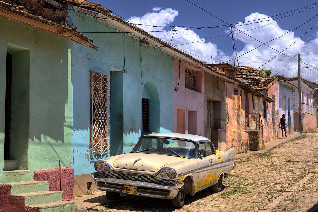 Classic American car parked on cobbled street outside brightly painted houses, Trinidad, Cuba, West Indies, Central America