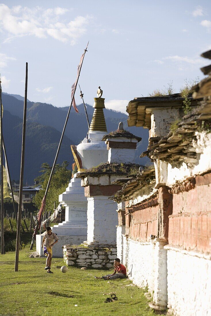 Bhutanese boys playing soccer near Buddhist chortens (stupa), Paro, Bhutan, Asia