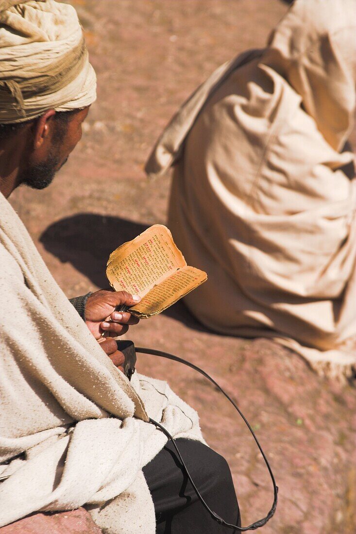 Pilgrim reads Holy Bible in Bet Maryam (St. Mary's) courtyard, Lalibela, Ethiopia, Africa