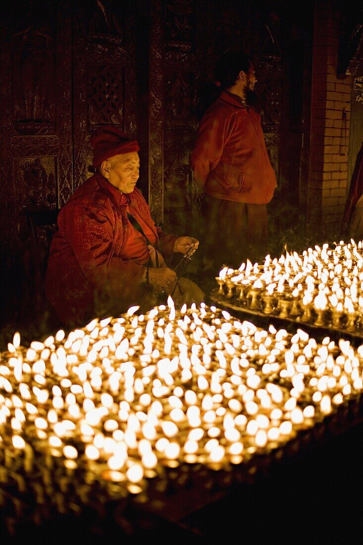 Monks light butter lamps on an auspicious night, Boudha stupa, Bodhnath, Kathmandu, Nepal, Asia