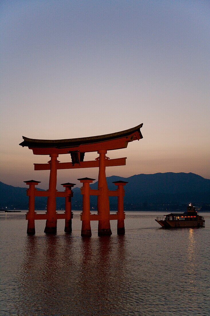 Vermillion coloured 'floating' torii gate (O-torii gate) illuminated at dusk, a Shinto shrine gate, UNESCO World Heritage Site, Itsuku-shima, Miyajima, Hiroshima, Honshu Island, Japan, Asia