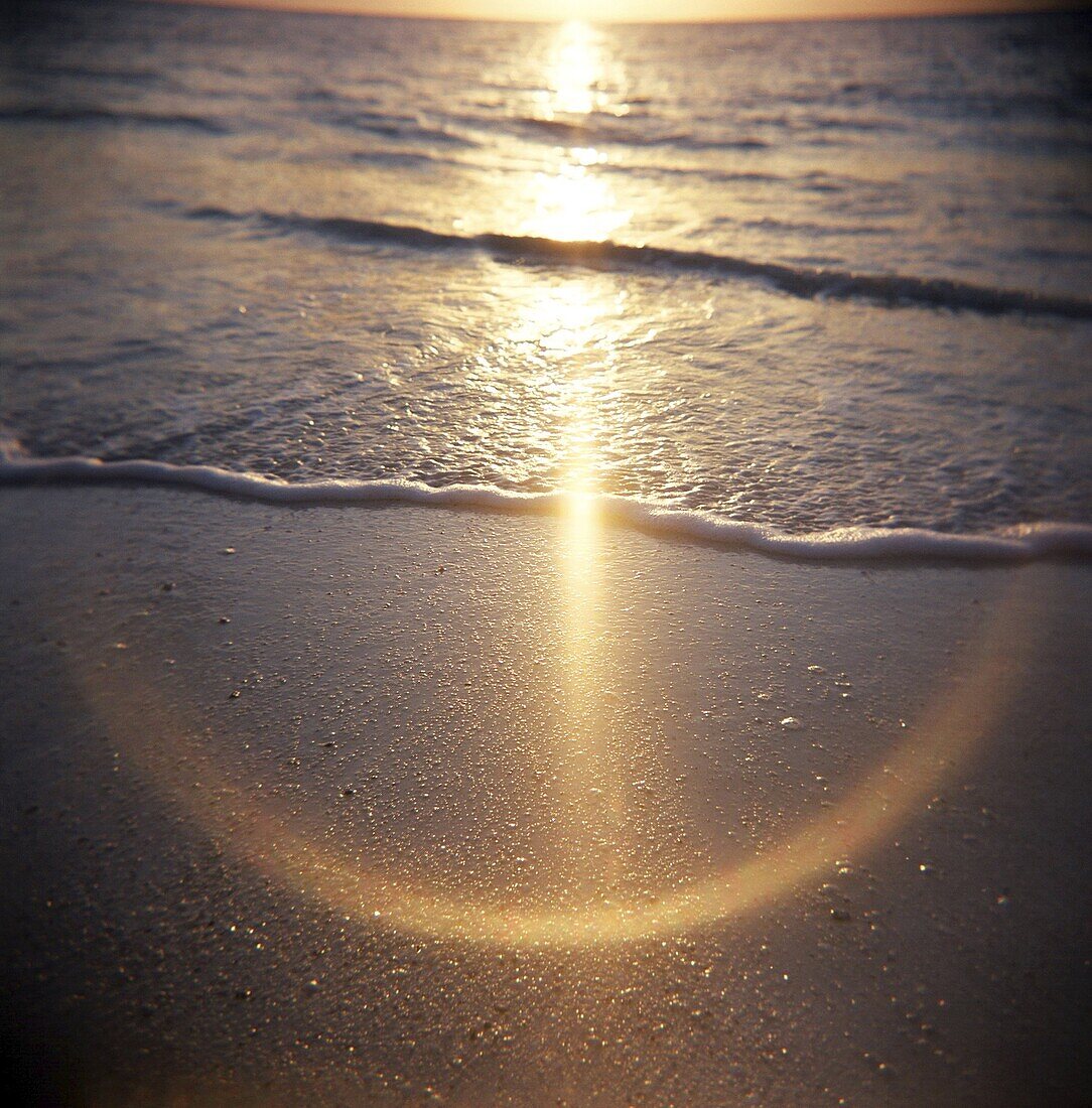 Image taken with a Holga medium format 120 film toy camera of sunlight reflecting on wet sand and sea at sunset, Stonetown, Zanzibar, Tanzania, East Africa, Africa