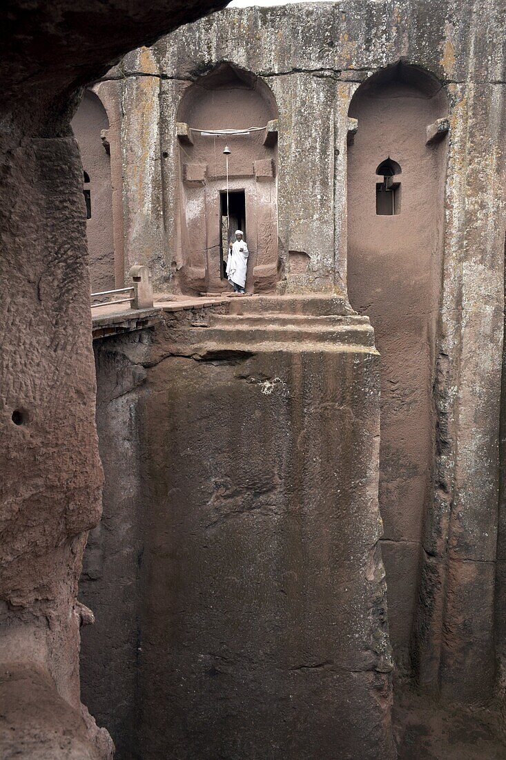 A priest stands at the entrance to the rock-hewn church of Bet Gabriel-Rufael, in Lalibela, UNESCO World Heritage Site, Ethiopia, Africa