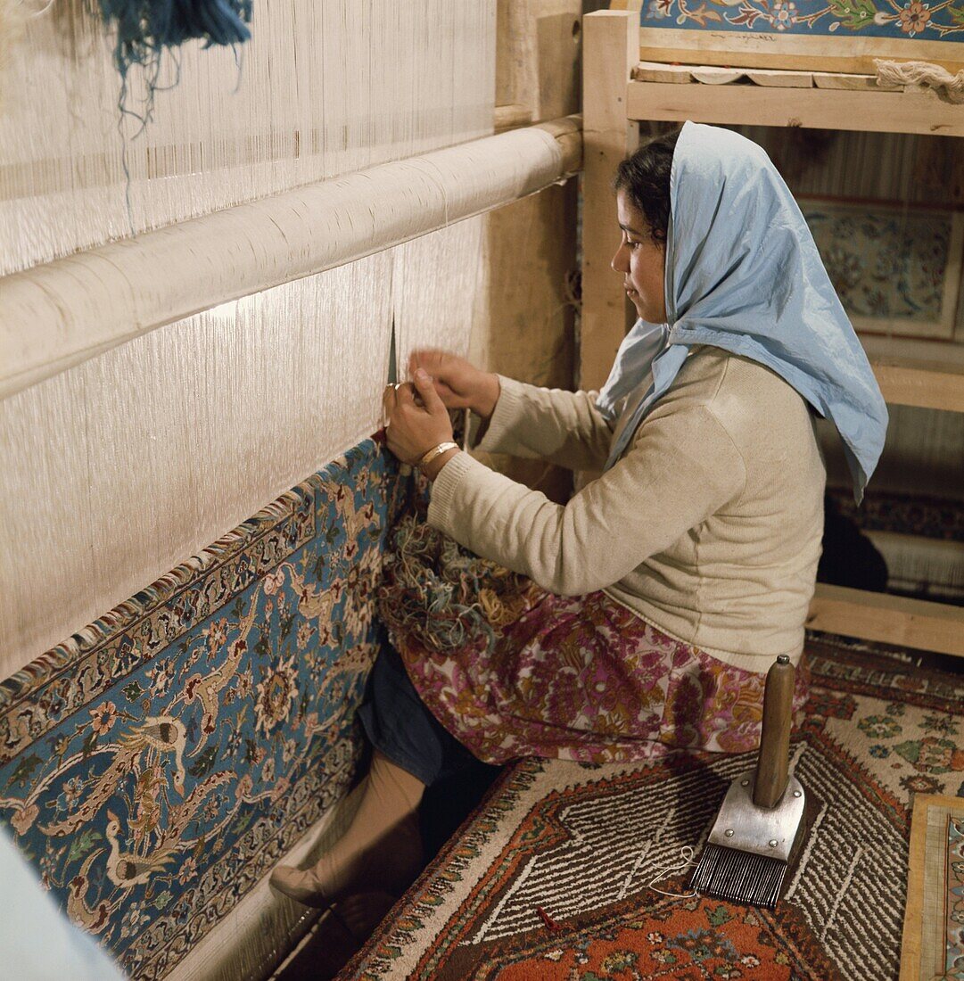 Young woman weaving carpet on loom, Iran, Middle East