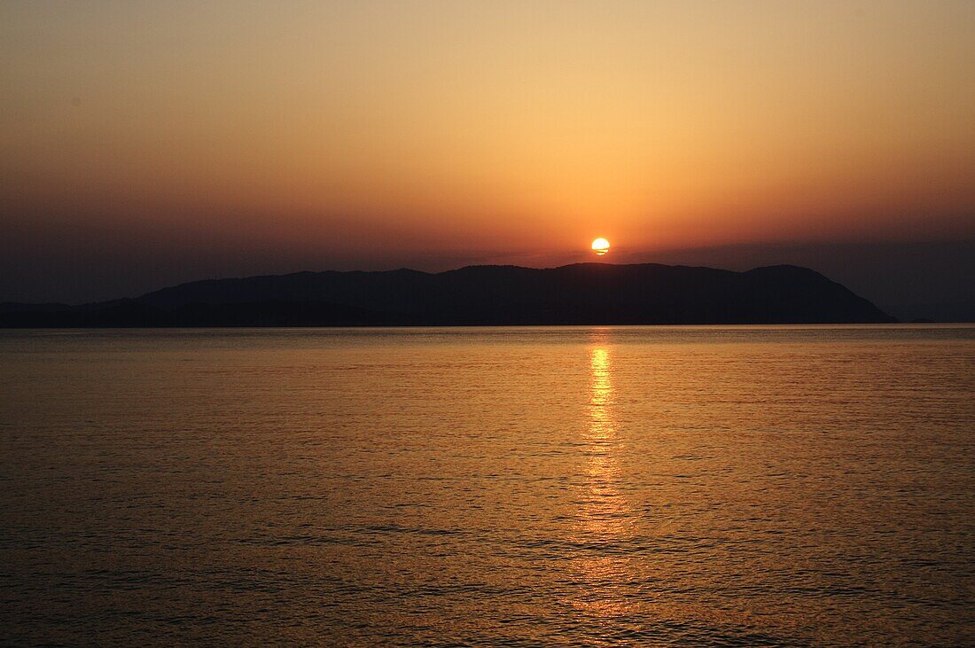 Sunset over the Aegean, taken from Loutraki, Skopelos, with Skiathos in background, Sporades Islands, Greek Islands, Greece, Europe