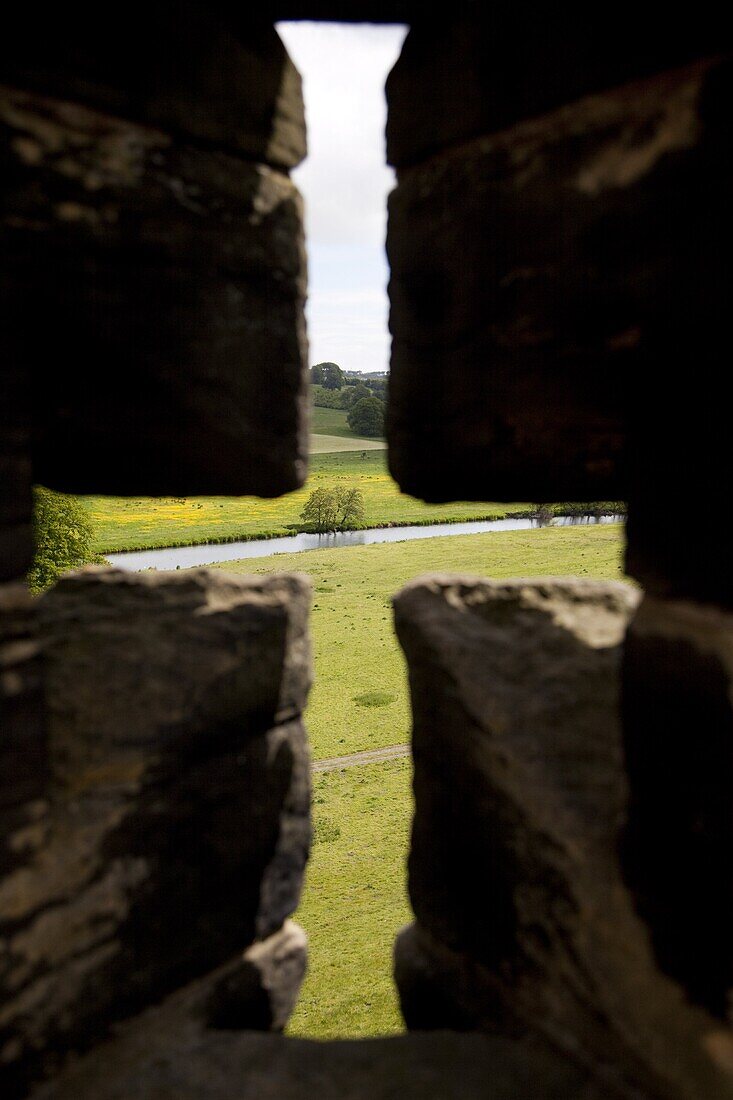 River Aln seen through arrow slit of the walls of Alnwick Castle, Northumberland, England, United Kingdom, Europe