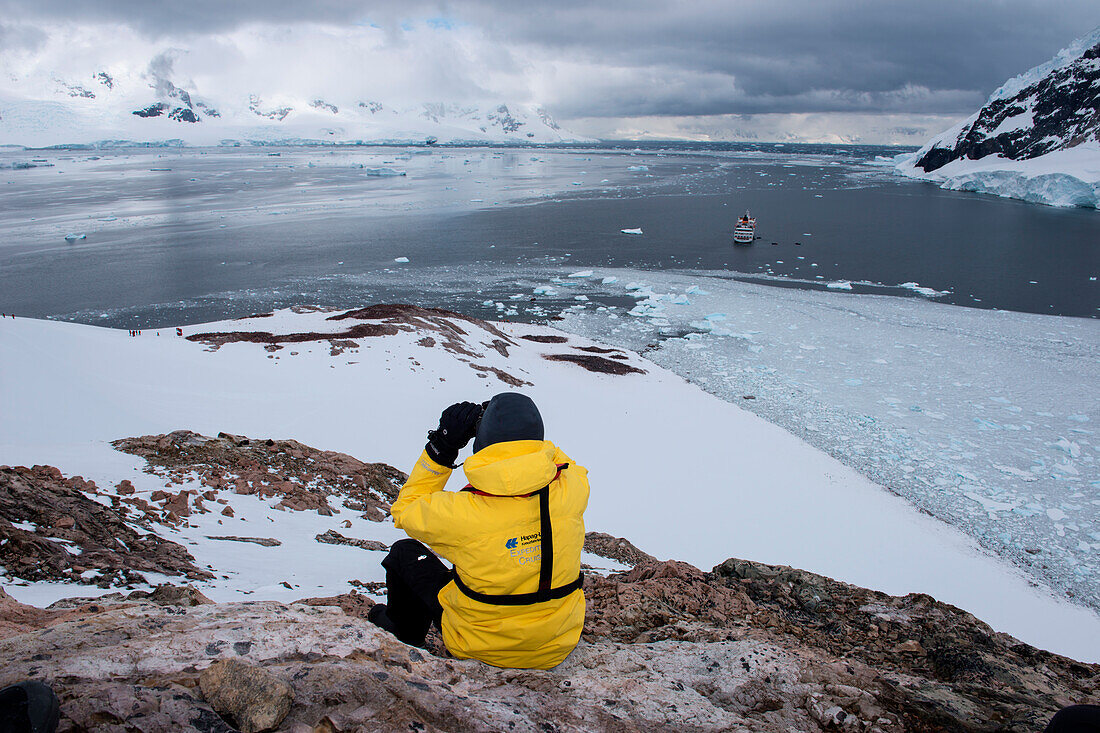 Ein Crew-Mitglied von Expeditions-Kreuzfahrtschiff MS Hanseatic (Hapag-Lloyd Kreuzfahrten) genießt den Ausblick von einem Berg, Neko Harbour, Grahamland, Antarktis
