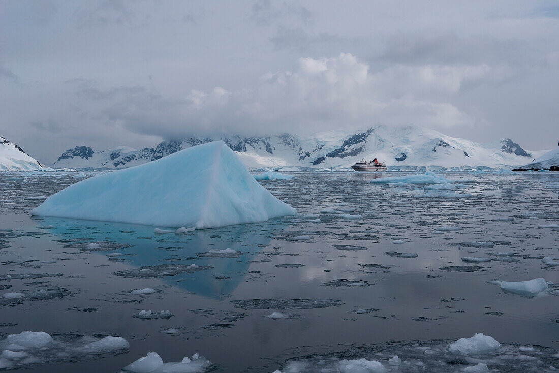Iceberg, ice floes and expedition cruise ship MS Hanseatic (Hapag-Lloyd Cruises), Paradise Bay (Paradise Harbor), Danco Coast, Graham Land, Antarctica