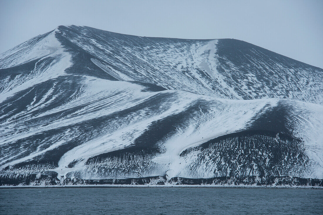 Snow on the volcanically formed hills creates a graphic, monochrome landscape, Deception Island, South Shetland Islands, Antarctica