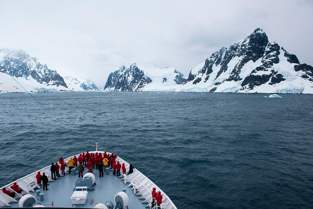 Passengers on bow of expedition cruise ship MS Hanseatic (Hapag-Lloyd Cruises) in Lemaire Channel, one of the most beautiful waterways on the northern Antarctic Peninsula and is one of many highlights of a cruise in this harsh area, Lemaire Channel, near 