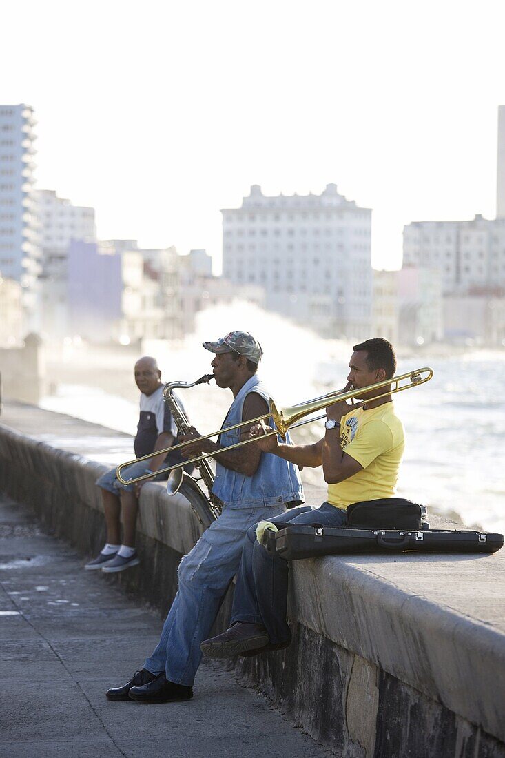 Musicians on The Malecon playing saxaphone and trombone with waves crashing against the shore in the background, Havana, Cuba, West Indies, Caribbean, Central America