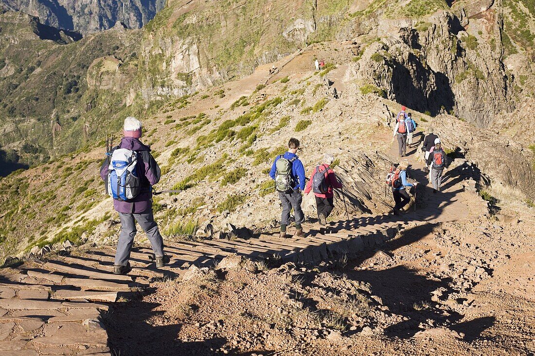 Hikers walk on on a footpath on the Pico do Ariero on the island of Madeira, Portugal, Europe
