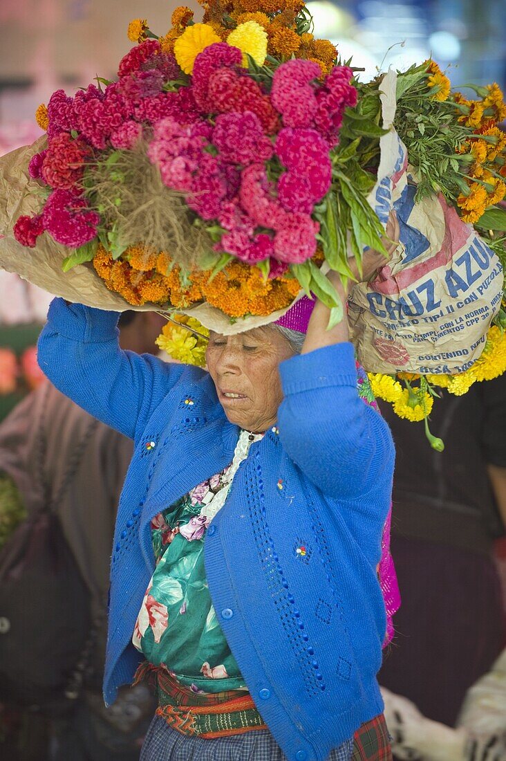 Woman carrying flowers at Tlacolula Sunday market, Oaxaca state, Mexico, North America