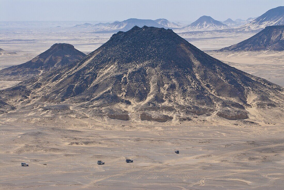 Jeeps passing little mountains in the Black Desert, Western Egypt, Egypt, North Africa, Africa