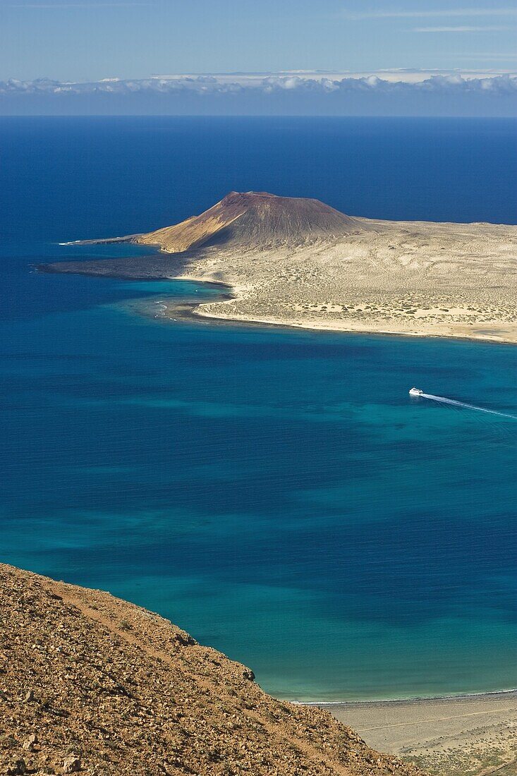 Volcanic cinder cone on Graciosa Island and the Graciosa to Lanzarote ferry in the Rio strait, seen from the Mirador del Rio on the north west coast of Lanzarote, Graciosa Island, Canary Islands, Spain, Atlantic, Europe