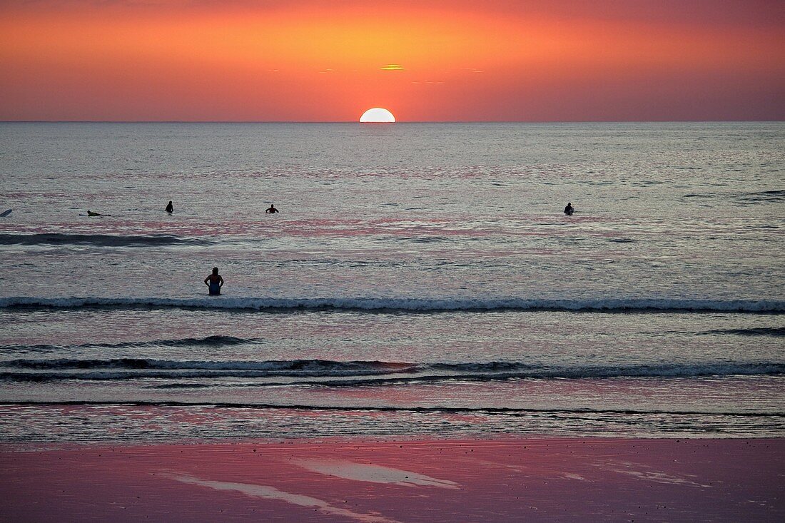 Surfers and swimmers at sunset off Playa Guiones beach, Nosara, Nicoya Peninsula, Guanacaste Province, Costa Rica, Central America