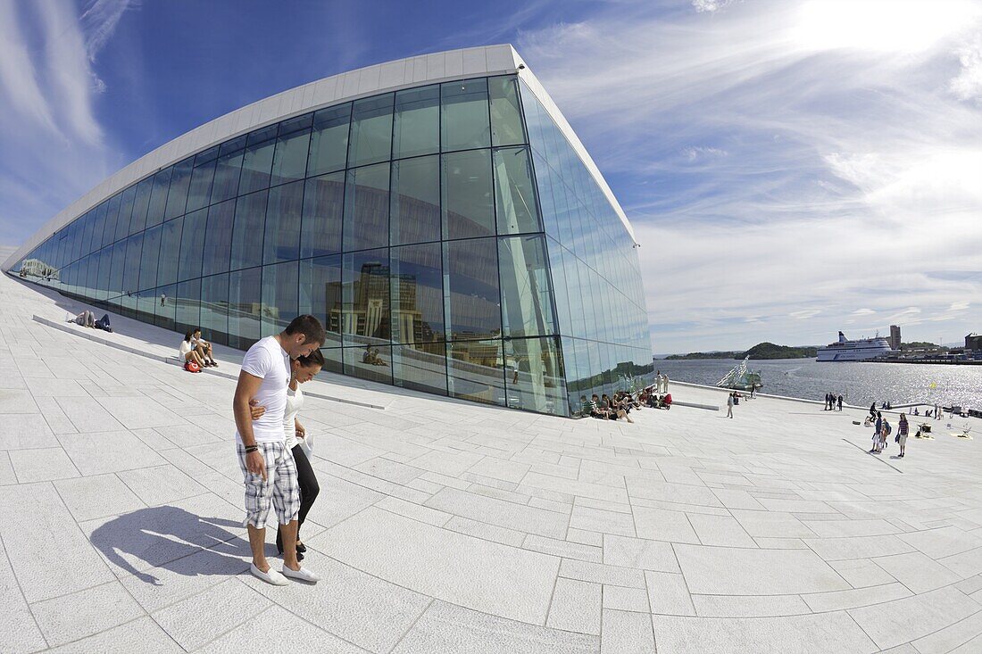 Young couple walking outside the Oslo Opera house exterior in summer sunshine, city centre, Oslo, Norway, Scandinavia, Europe