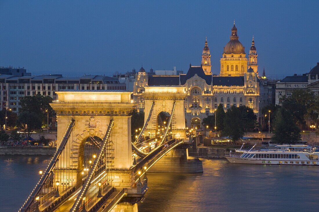 Night view of the Chain Bridge (Szechenyi Lanchid), illuminated, over the River Danube with the Gresham Hotel, St. Stephen's basilica, and the Pest side behind, Budapest, Hungary, Europe