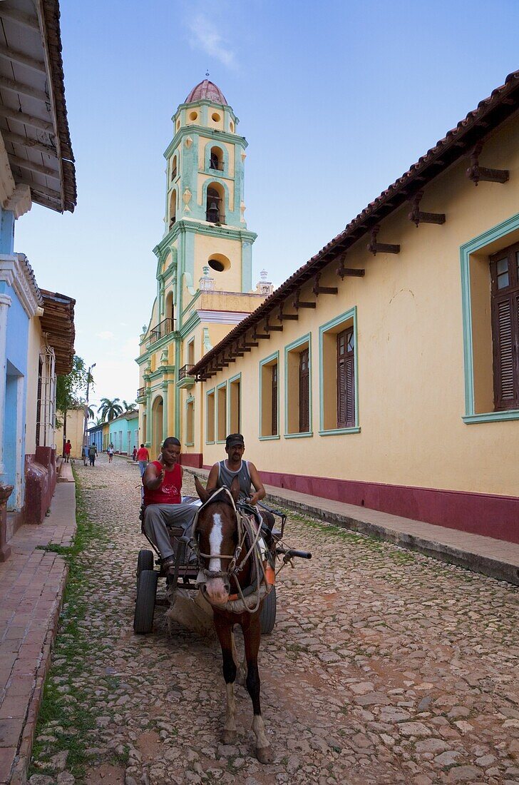 Two men on horse-drawn cart travelling along a quiet street in Trinidad, Sancti Spiritus Province, Cuba, West Indies, Caribbean, Central America