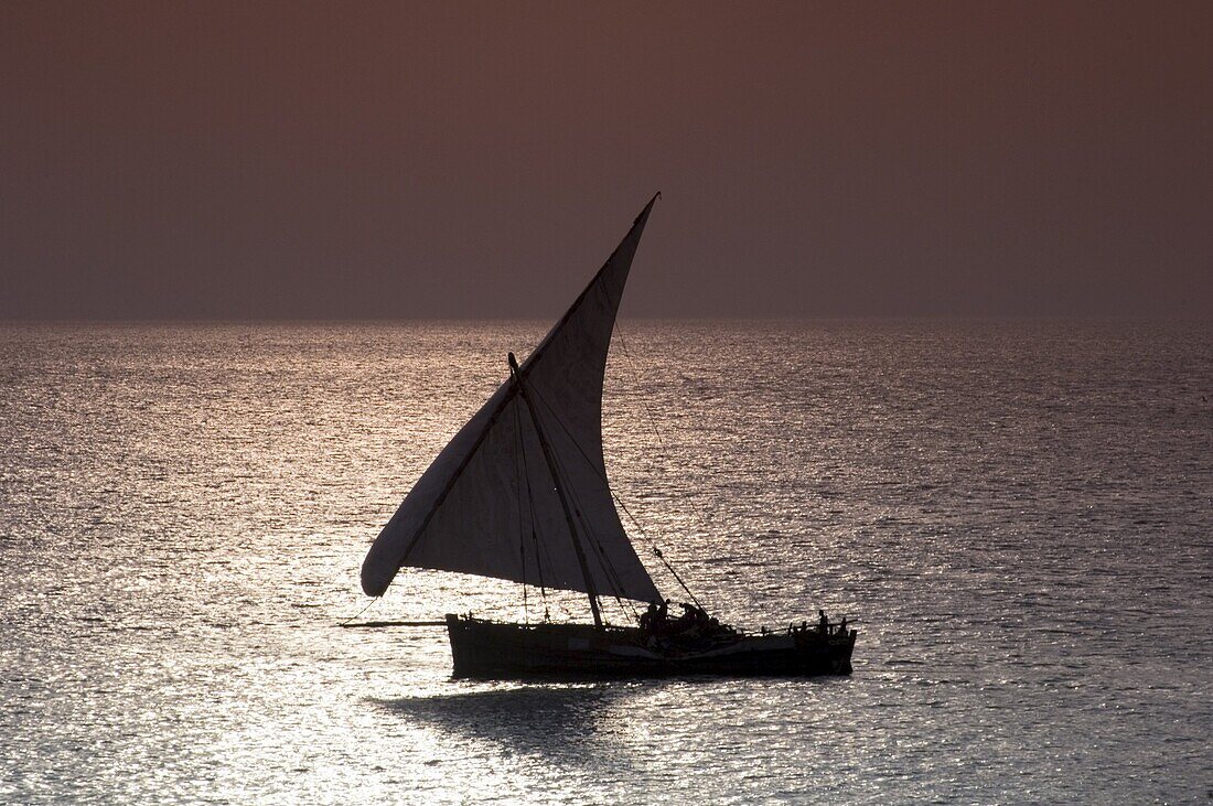 A traditional wooden dhow sailing near Stone Town at sunset, Zanzibar, Tanzania, East Africa, Africa