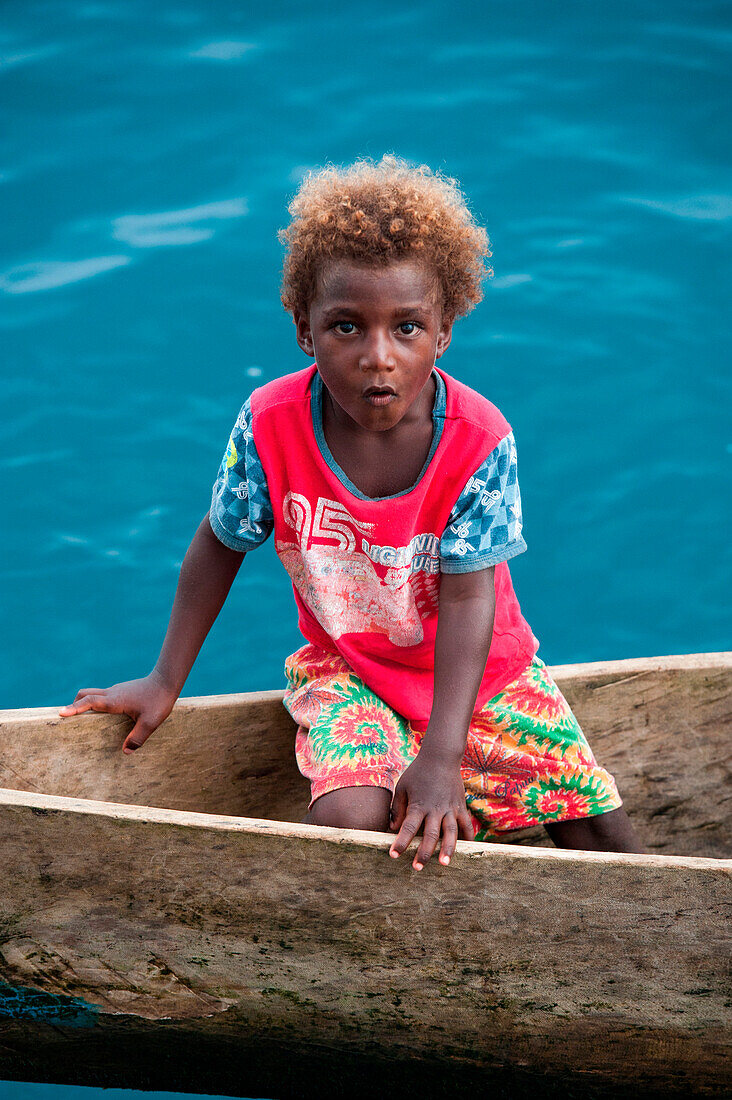 Junges dunkelhäutiges Mädchen mit blonden Locken in einem Kanu, Lorengau, Manu Provinz, Papua-Neuguinea, Südpazifik